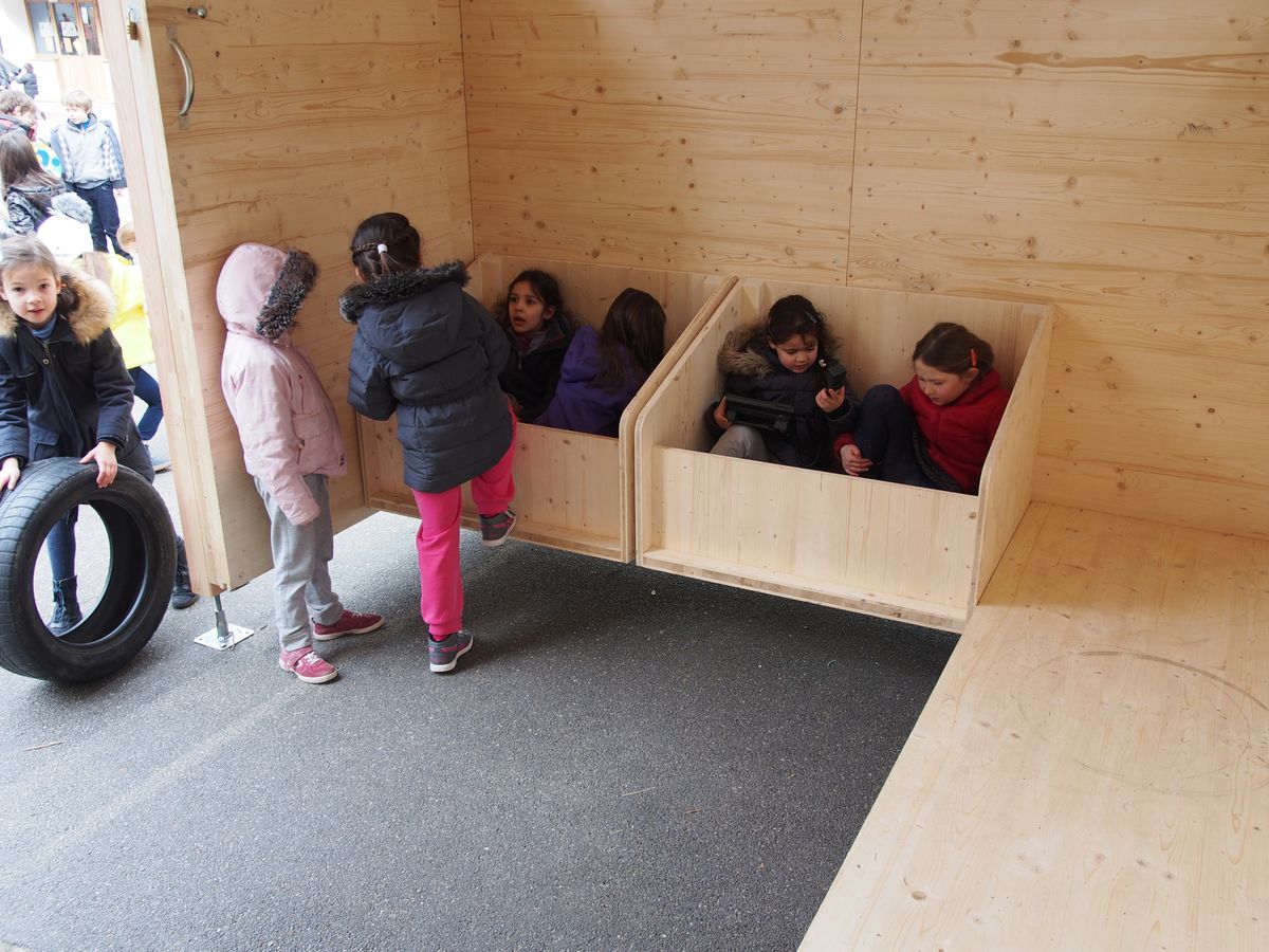 Des enfants installés dans les bacs de rangement de la Boîte à Jouer