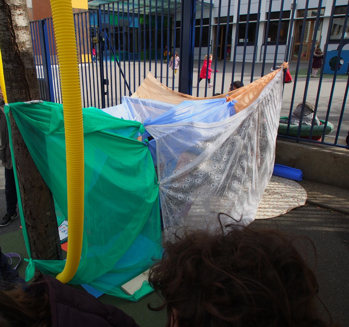 Des enfants jouent sous une cabane de tissus colorés