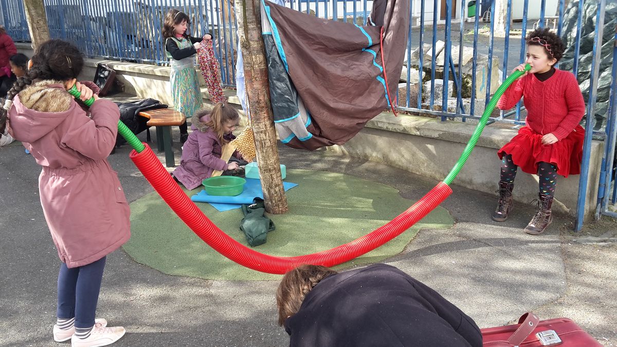 Des enfants se parlent à travers de longs tubes souples