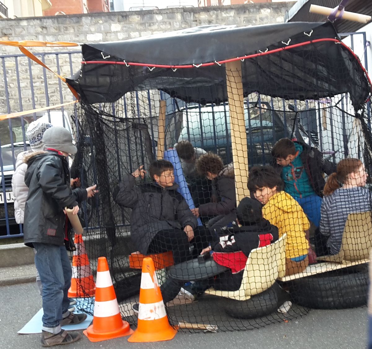 Des enfants réunis sous une tente de filet et de bâches